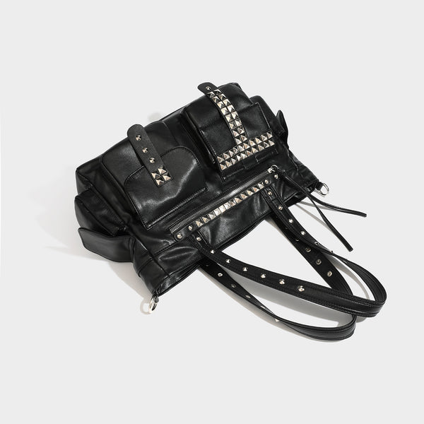 Black leather-look tote bag with silver pyramid studs on handles and front panel, multiple flap and zip exterior pockets