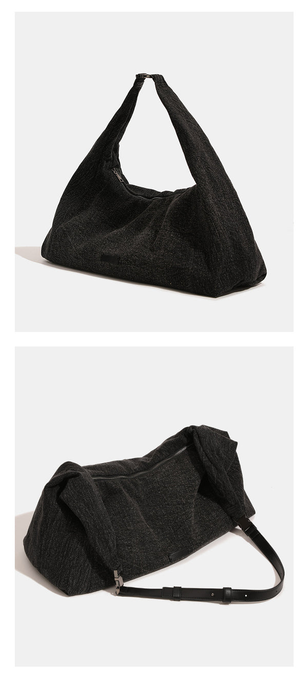 Oversized slouchy black textured canvas hobo shoulder bag with zip-top closure and adjustable dark-hardware strap, detail