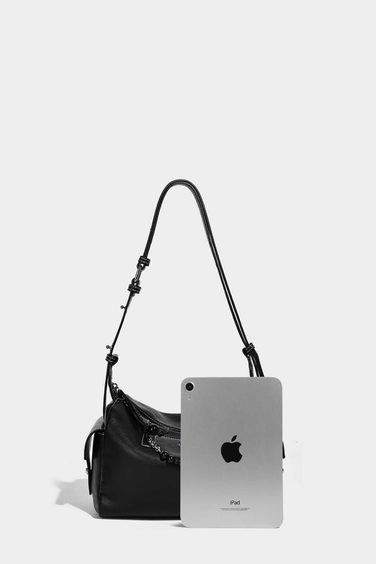 Small slouchy moto-style crossbody bag in smooth matte leather-look finish with white contrast stitching, silver-tone, detail