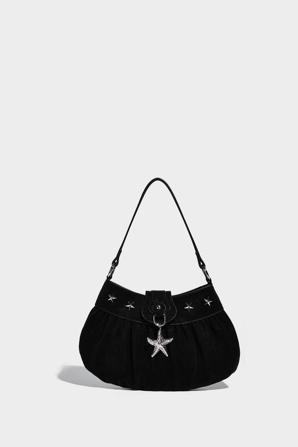 Ruched shoulder bag with curved flap, silver star studs, dangling starfish charm, and adjustable crossbody strap, detail view