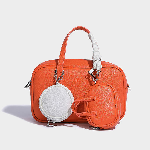 Structured pebbled leather-look Boston bowling bag in tan with blue detachable round mini pouch, dual top handles, and