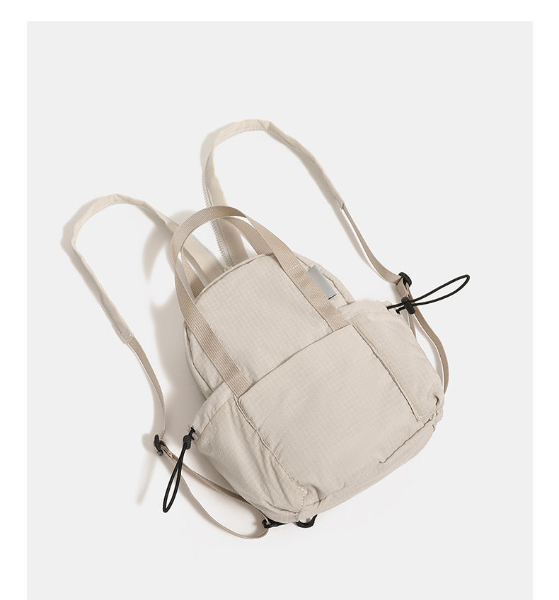Mini rounded convertible backpack handbag in matte ripstop fabric with dual top handles, adjustable straps, and side, detail