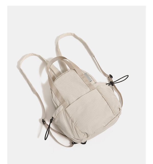 Mini rounded convertible backpack handbag in matte ripstop fabric with dual top handles, adjustable straps, and side, detail