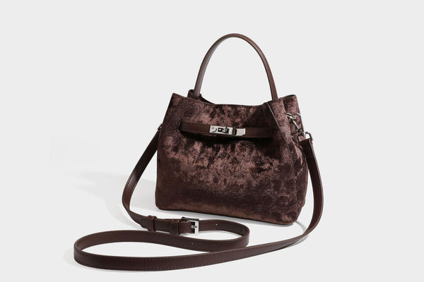 Small structured bucket satchel in embossed velvet-texture fabric with silver turn-lock hardware, rounded top handle, and