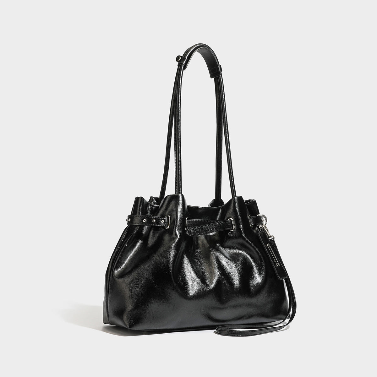 Glossy black slouchy shoulder bag with gathered top, twin long straps, silver-tone hardware, and detachable crossbody strap