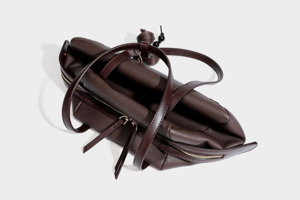 Structured trapezoid shoulder bag in dark brown pebbled leather-look finish with slim double straps, top zip closure, side