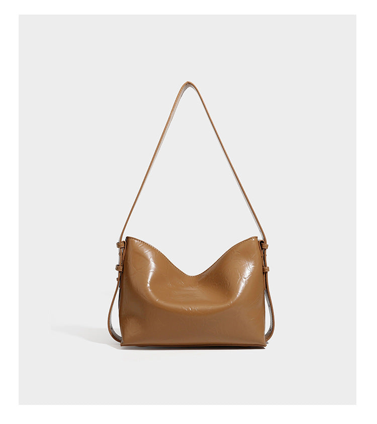Lässige Hobo-Schultertasche mit offenem oberen Abschluss in glänzender karamellfarbener Lederoptik mit goldfarbenen Logo-Beschlägen und langem, verstellbarem