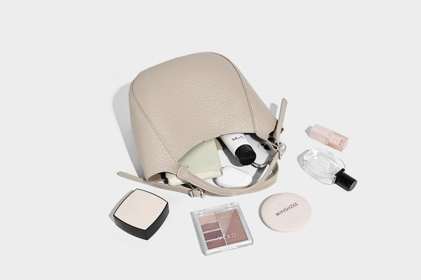 Small pebbled half-moon shoulder bag with dual top handles, detachable crossbody strap, and silver-tone hardware, detail view