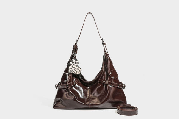 Glänzende dunkelbraune, lässig geschnittene Hobo-Schultertasche mit Riemendetail mit silberfarbenen Ösen, Reißverschlussfach auf der Vorderseite und Herz mit Leopardenmuster