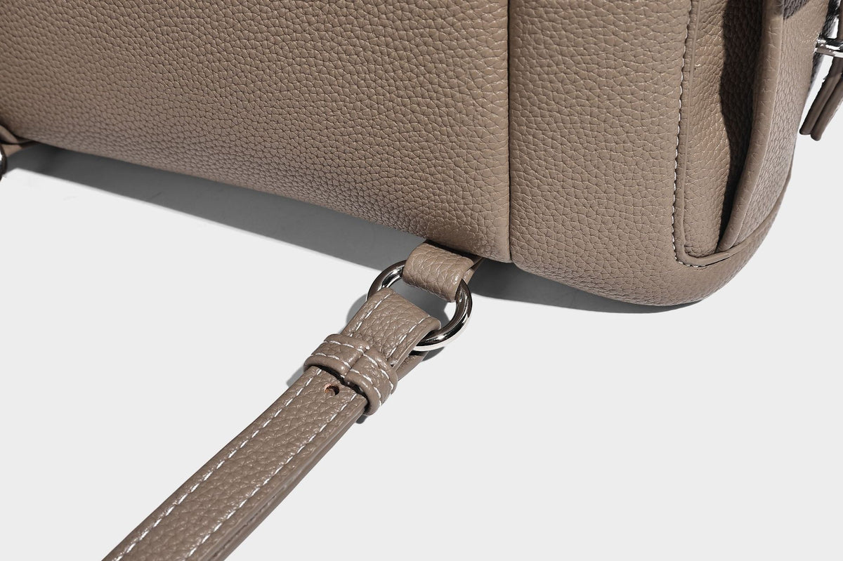 Compact pebbled leather-look flap drawstring backpack handbag with side pockets, top handle, and silver-tone hardware, detail