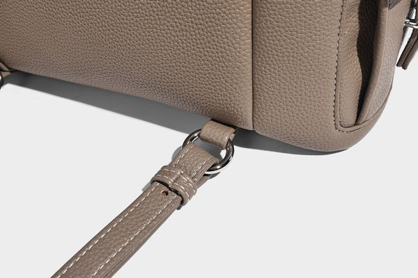 Compact pebbled leather-look flap drawstring backpack handbag with side pockets, top handle, and silver-tone hardware, detail