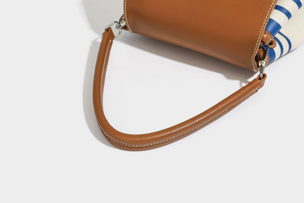 Cream canvas bucket bag with blue horizontal stripes, tan leather-look flap and trim, drawstring closure, silver-tone, detail