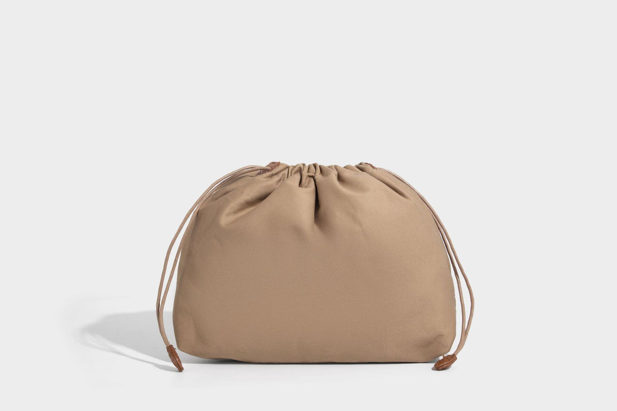 Structured woven herringbone tote bag with braided double shoulder handles in tan brown, shown with matching drawstring