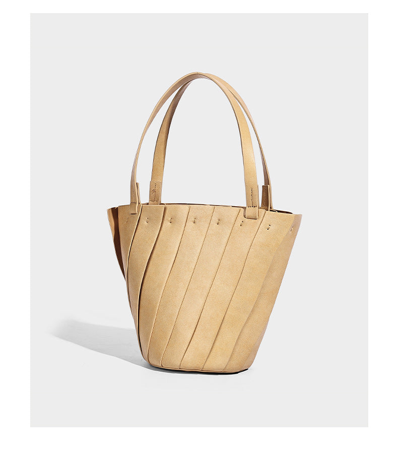 Structured bucket tote bag with vertical panel exterior, dual top handles, and detachable shoulder strap in tan leather-look