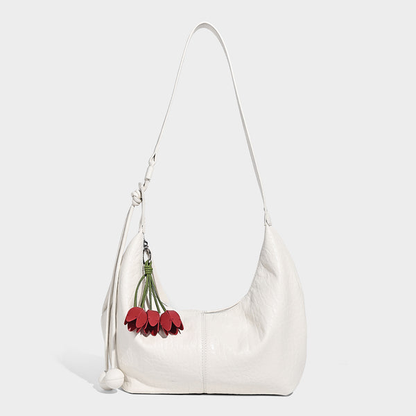 Slouchy crescent half-moon shoulder bag in pink pebbled textured finish with floral charm and knotted side detail, detail