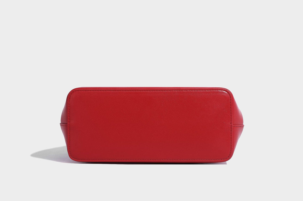 Small structured shell top-handle bag in red with heart charm and braided cord detail, smooth leather-look finish, detail