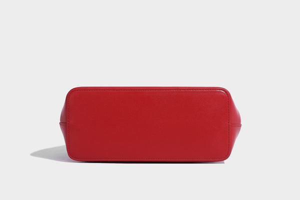 Small structured shell top-handle bag in red with heart charm and braided cord detail, smooth leather-look finish, detail