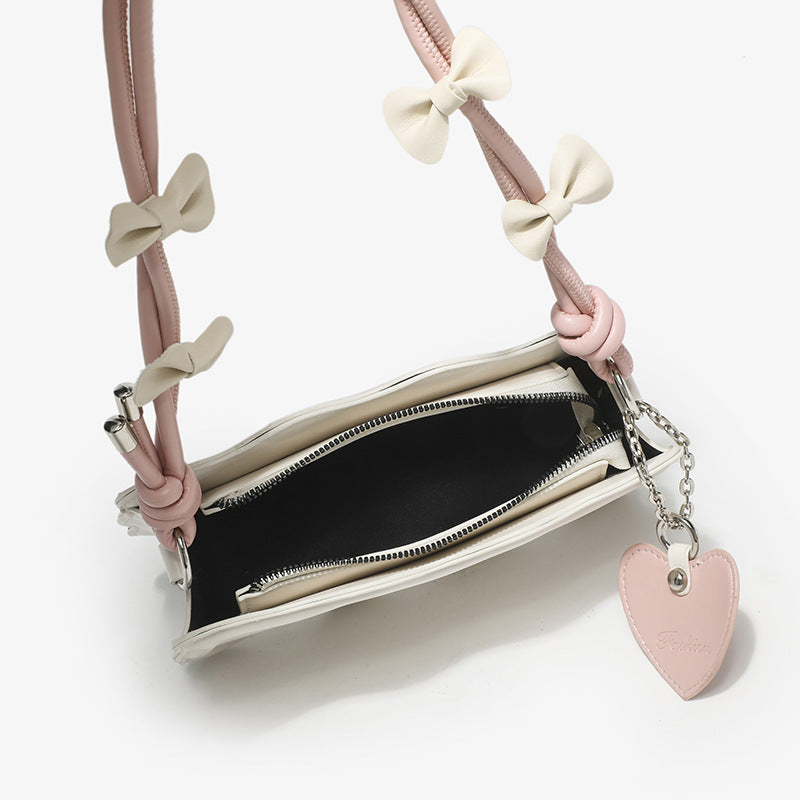 Small structured scalloped-edge shoulder bag with bow-tied pink cord strap and silver heart charm pendant, detail view 4