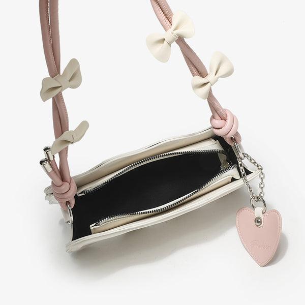 Small structured scalloped-edge shoulder bag with bow-tied pink cord strap and silver heart charm pendant, detail view 4