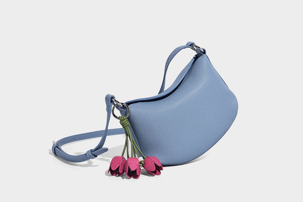 Small crescent half-moon bag in pebbled leather-look finish with braided top handle, silver-tone ring hardware, and, detail