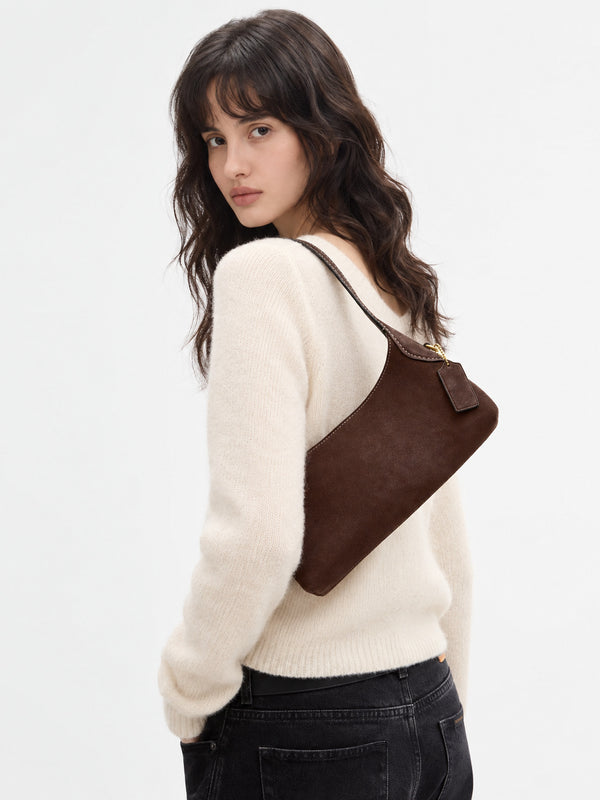 Slim crescent-silhouette shoulder bag in chocolate brown suede-look finish with contrast topstitching, top zip closure, thin