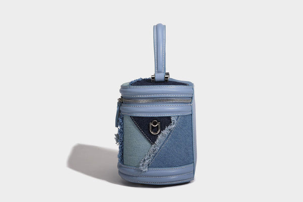 Mini cylindrical barrel bucket bag in denim patchwork with frayed edges, smooth leather-look trim, zip-around top closure