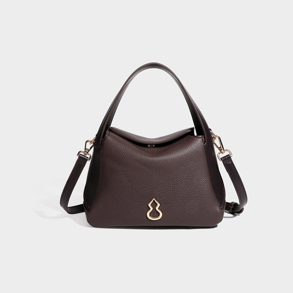 Structured pebbled leather-look shoulder bag with flap top, gold-tone emblem hardware, dual top handles, and detachable