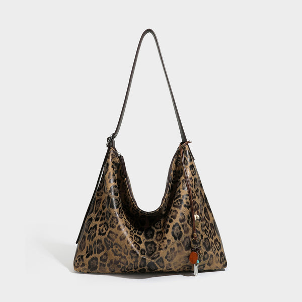 Slouchy leopard print hobo shoulder bag with glossy coated finish, top zipper closure, dark brown trim, and dangling charm