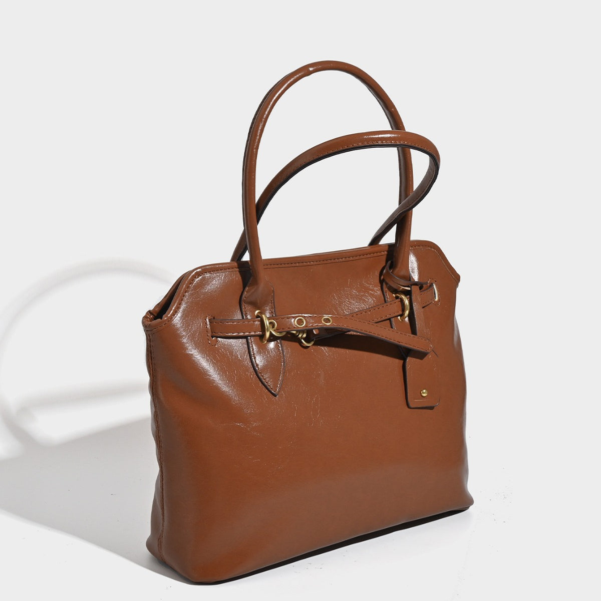 Structured cognac brown leather-look tote bag with decorative belt strap and gold-tone hardware, detail view 2