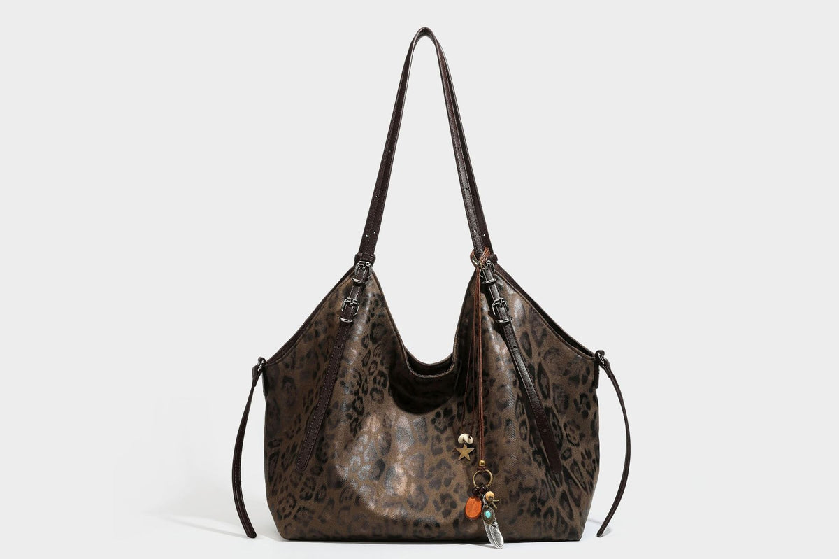 Slouchy leopard-print shoulder tote bag in tan and brown with long double straps, side tie straps, and dangling charm, detail