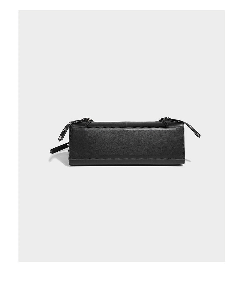Black structured rectangular satchel bag with silver-tone rivets, large front buckle strap, zip pockets, dual top handles