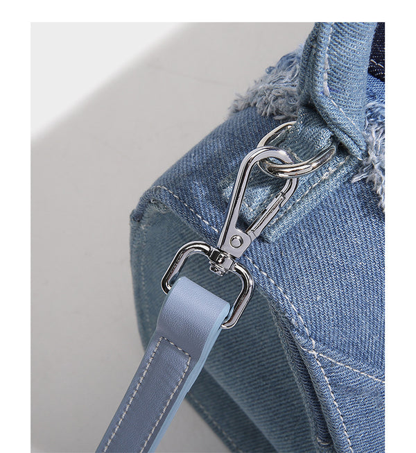 Structured patchwork denim trapezoid satchel bag with frayed panel trim, rounded top handle, and silver-tone hardware, detail