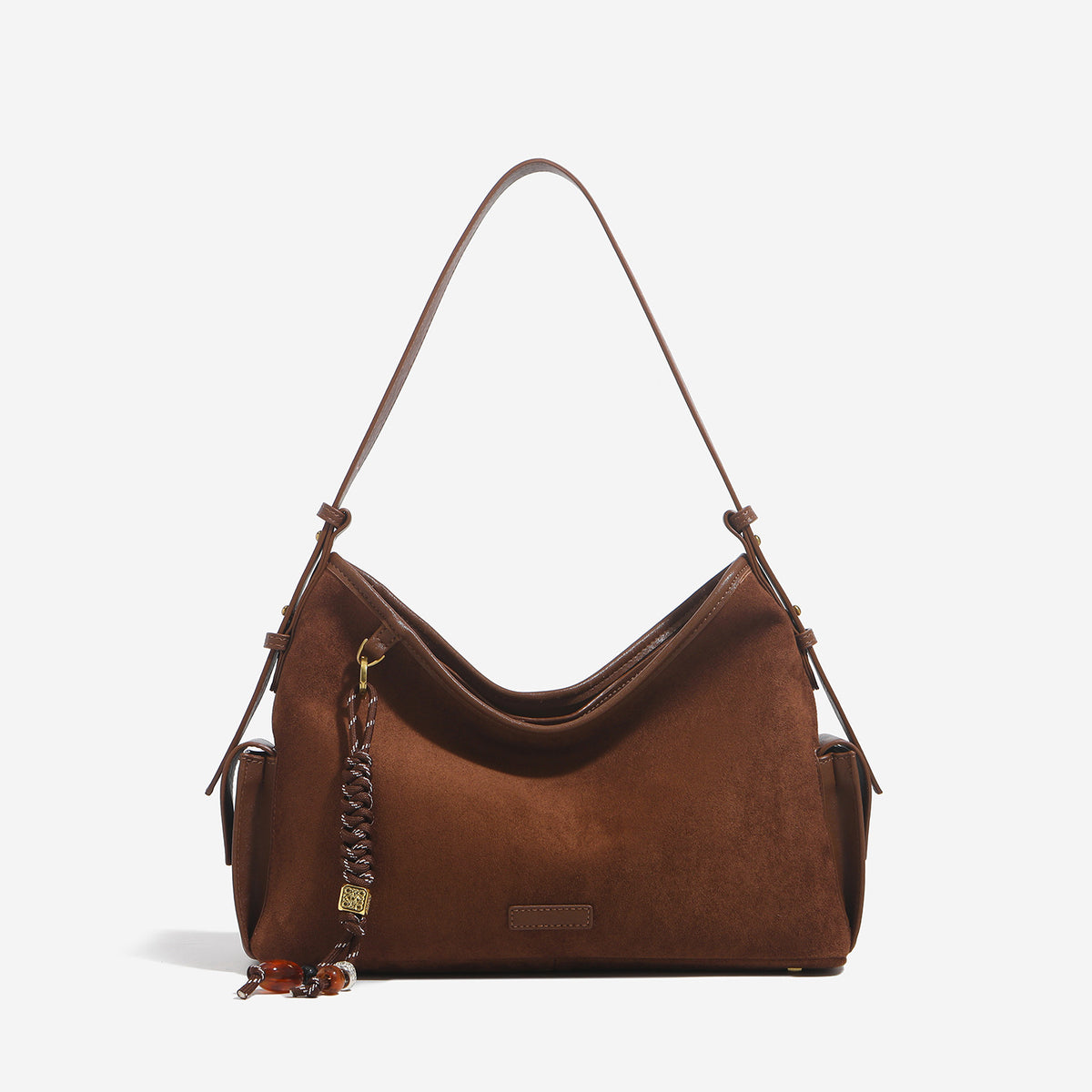 Caramel brown slouchy hobo shoulder bag with matte suede-like finish, braided tassel charm, brass-tone hardware, and, detail