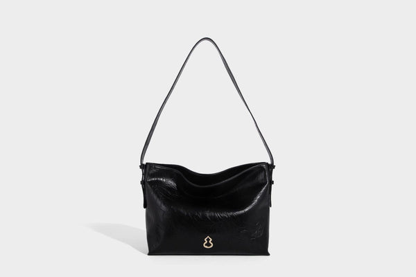 Large slouchy hobo shoulder bag in glossy crinkle leather-look finish with gold-tone emblem hardware and adjustable strap