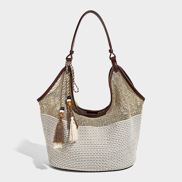 Two-tone beige and cream woven straw hobo shoulder bag with brown leather-look trim, long shoulder strap, and tassel-bead