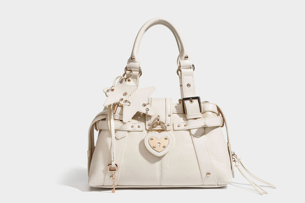Structured leather-look satchel bag with heart padlock charm, star charm, gold-tone buckle hardware, dual top handles, and