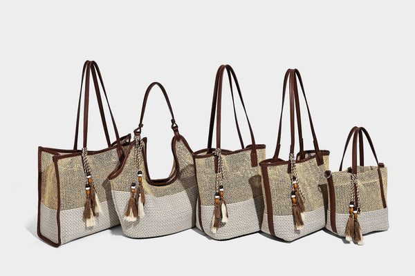 Two-tone beige and cream woven straw hobo shoulder bag with brown leather-look trim, long shoulder strap, and tassel-bead
