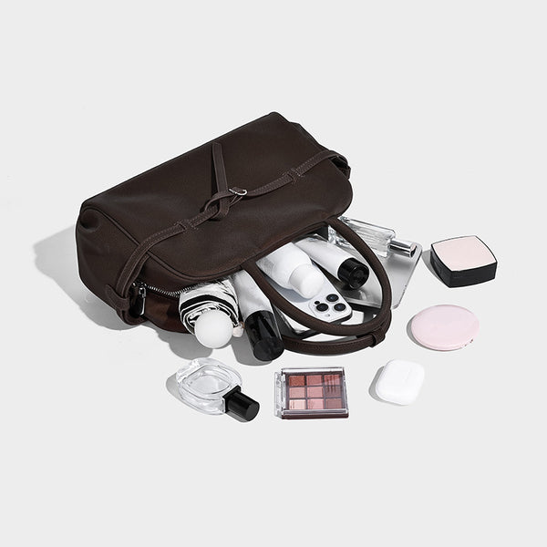 Strukturierte Henkeltasche mit matter, genarbter Oberfläche, umlaufendem Riemen mit Ringbeschlägen, zwei Tragegriffen und abnehmbarem Umhängeriemen
