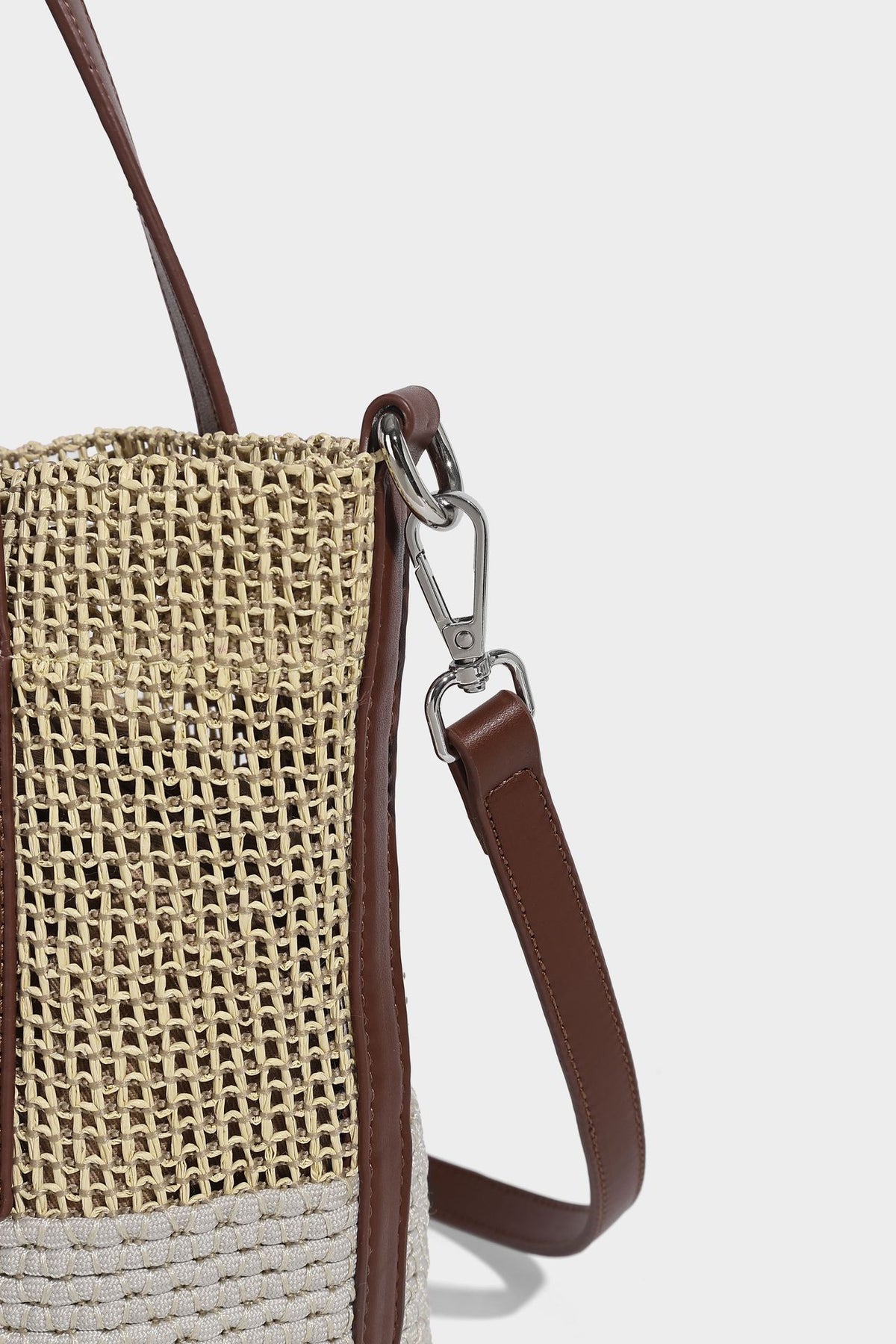 Two-tone open-weave tote bag in beige and cream with brown leather-look handles, tassel bead charm, and detachable
