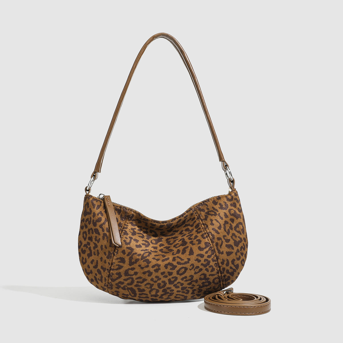Brown and tan leopard print crescent hobo shoulder bag with zip top closure, front zip pocket, and adjustable silver-tone
