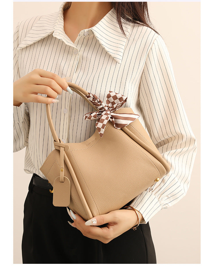 Structured pebbled tote bucket bag in apricot with braided top handle, checkered bow scarf, gold-tone hardware, and, detail