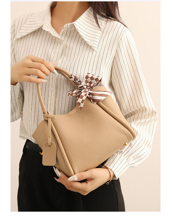 Structured pebbled tote bucket bag in apricot with braided top handle, checkered bow scarf, gold-tone hardware, and, detail