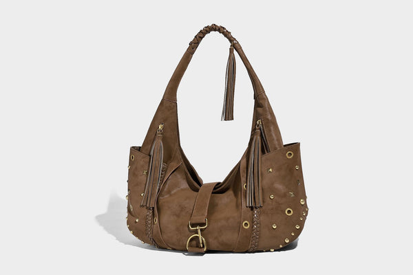 Slouchy crescent hobo bag in matte brown suede-like finish with gold-tone studs, grommets, braided top handle, tassel side