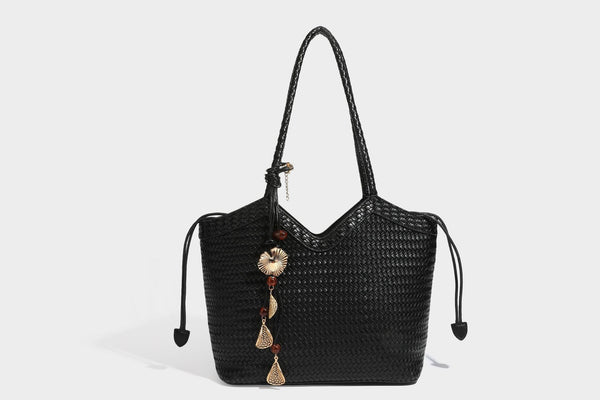 Olivgrüne Tote-Bag in Korbgeflecht-Optik mit dunkelbraunen geflochtenen Schulterriemen, seitlichen Kordelzügen und Perlenanhänger in Goldoptik