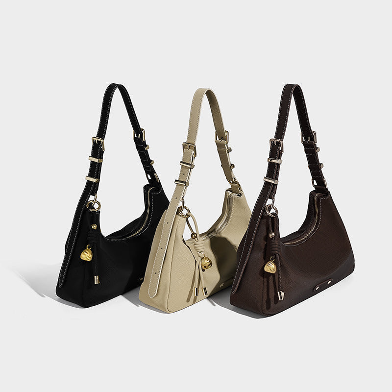 Crescent hobo shoulder bag in pebbled leather-look finish with top zipper, adjustable strap, gold-tone ring hardware, and
