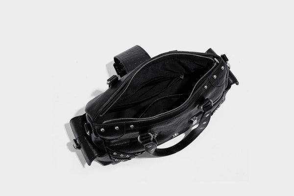 Schwarze, glänzende Henkeltasche mit genarbter Struktur, silberfarbenen Nieten, Riemendetail mit Schnalle, zwei Henkeln und breitem, mit Nieten besetztem Schulterriemen