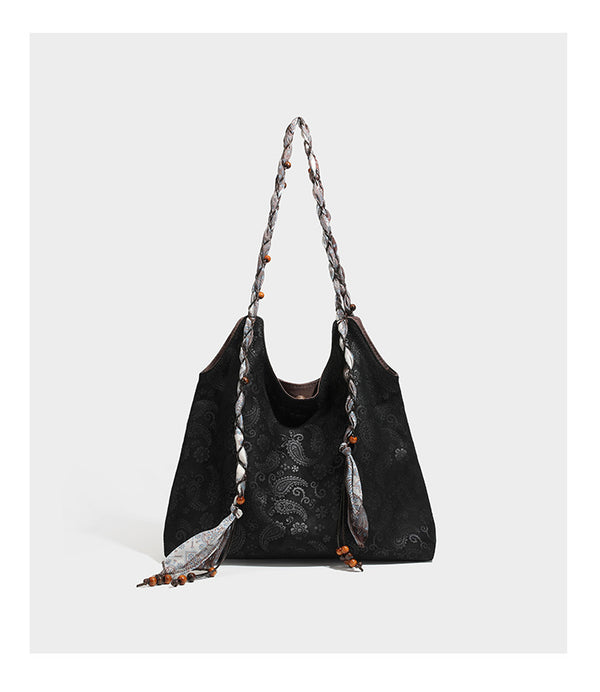 Slouchy paisley-embossed suede-look shoulder tote bag with braided patterned fabric straps and wood bead accents, detail view