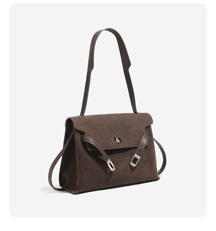 Structured trapezoidal flap satchel bag with silver-tone turn-lock clasp, decorative front strap tabs, gusseted sides, and