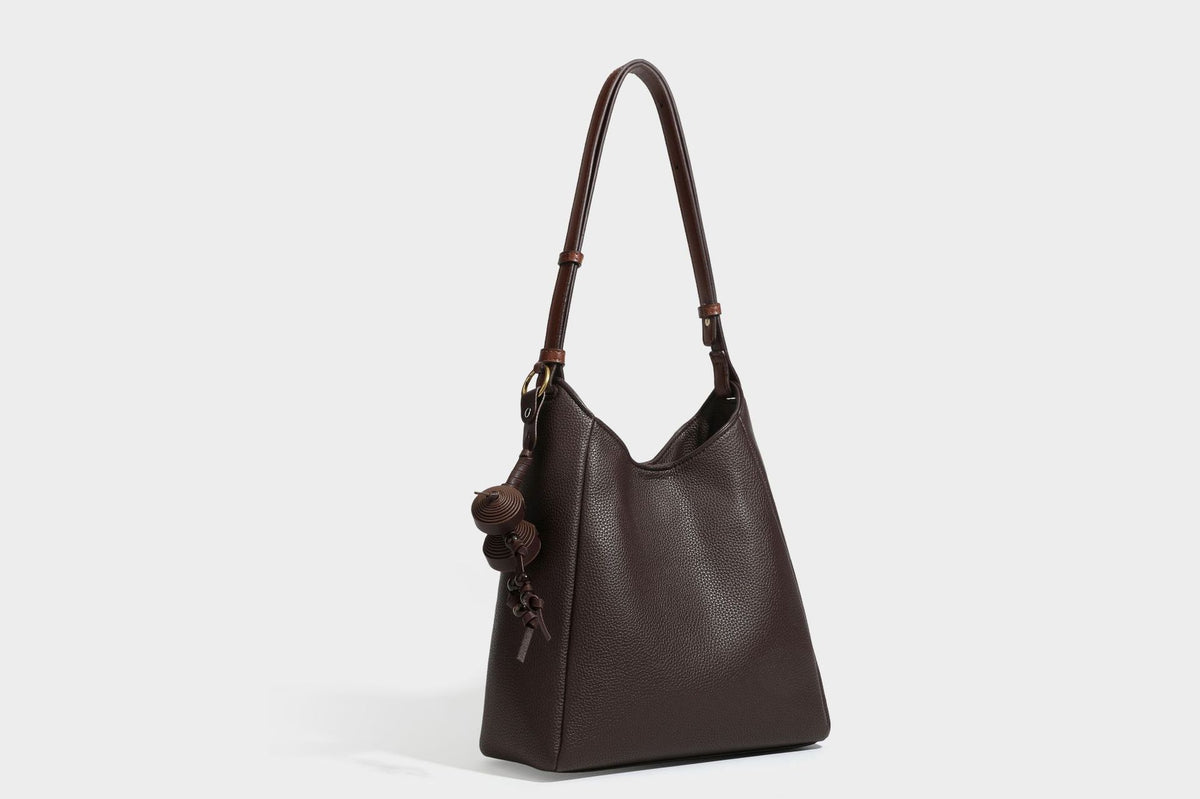 Hobo-Schultertasche in dunklem Espresso mit genarbter Oberfläche, warmen cognacfarbenen Details, verstellbarem schmalem Riemen, goldfarbenen Ringbeschlägen und geknotetem
