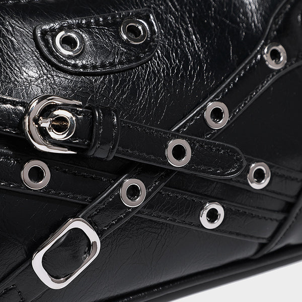 Compact moto-inspired shoulder bag with crisscross grommet strap detail, glossy textured finish, and adjustable crossbody